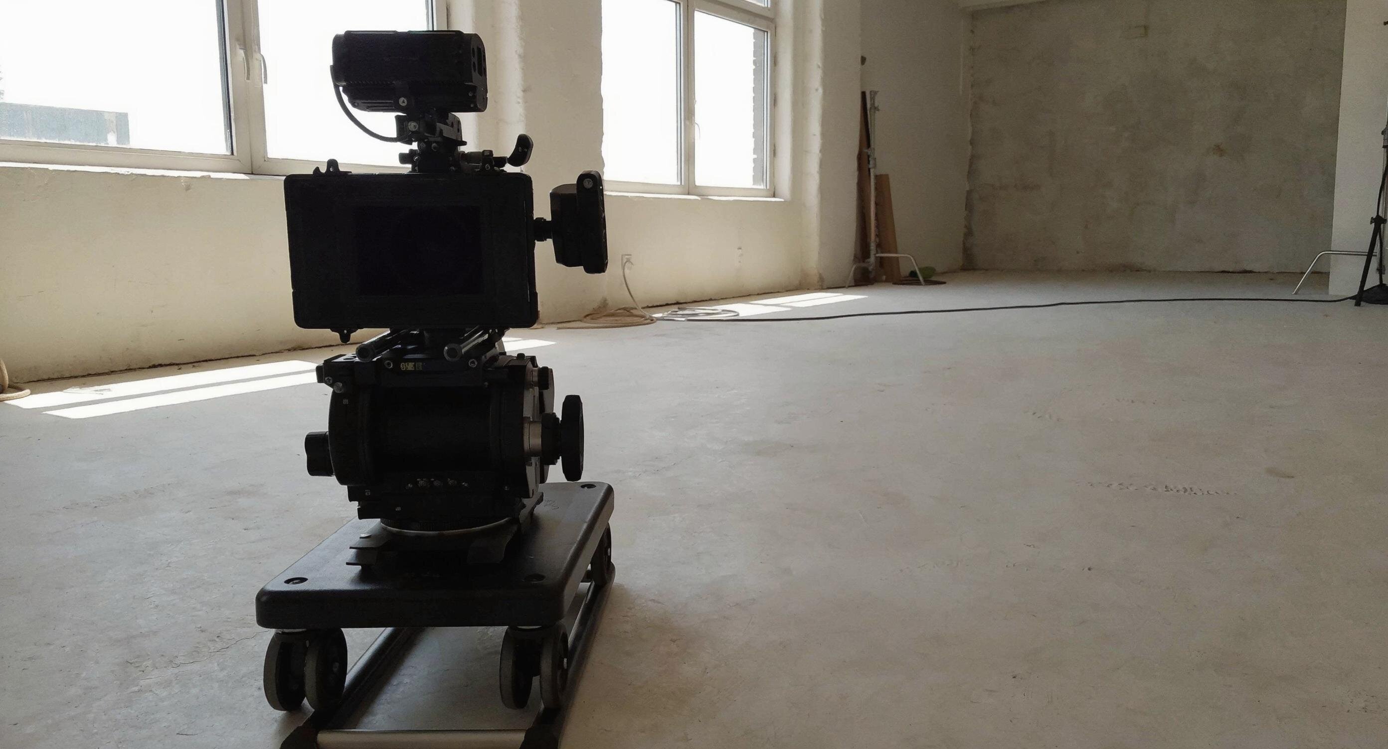 Professionelle Videokamera auf einem Dolly in einem hellen, lichtdurchfluteten Produktionsraum