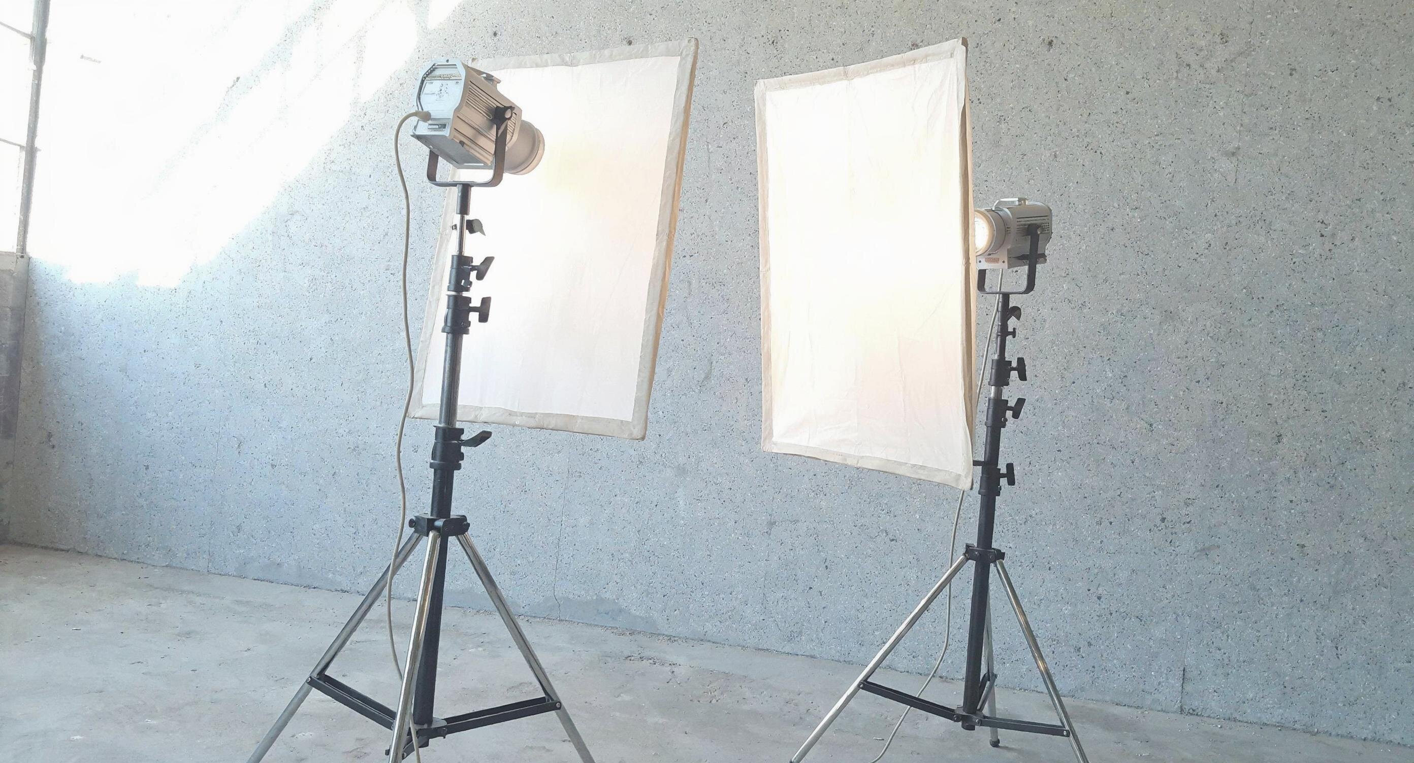 Zwei Studioleuchten mit Softbox-Diffusoren auf Stativen vor einer hellen Betonwand